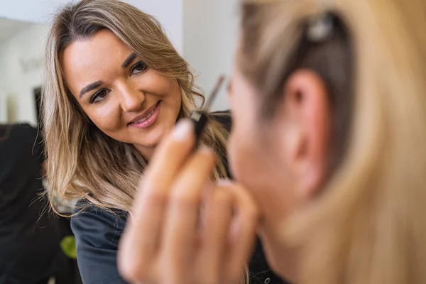 Makeup artist using brow pencil on customer in beauty salon