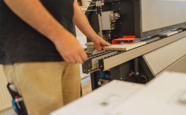 İşçi atölyedeki kesme makinesine kontrplak koyuyor.