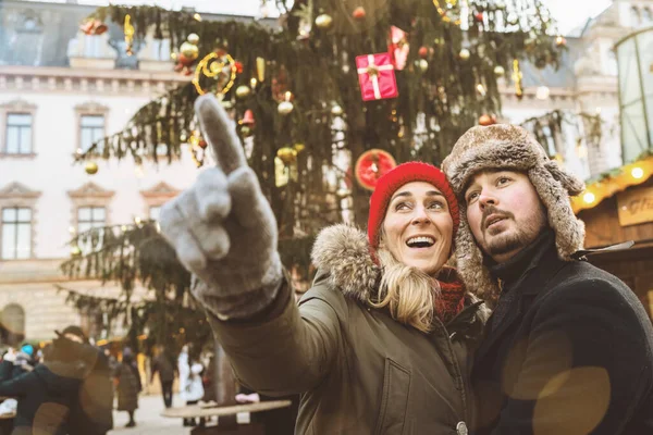 Surprised woman pointing with her hand to show her Boyfriend something on Christmas market at winter time in germany