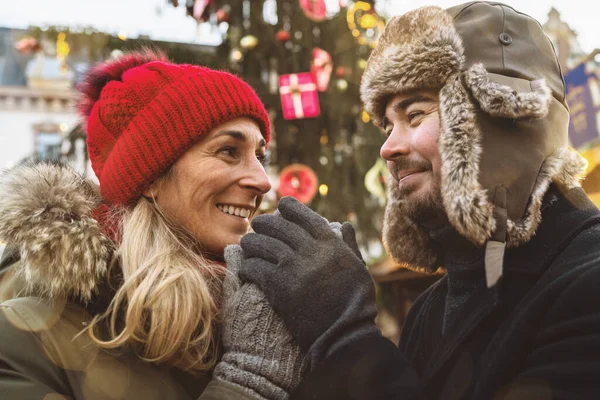 Romantik çift Noel pazarında sıcak şarabın tadını çıkarıyor.