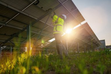 Bir güneş alanının elektrik dağıtım kutusunda voltaj testi yapan bir teknisyen. Alternatif enerji ekolojik konsept görüntüsü.