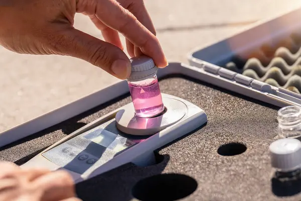 テストキットにデジタル分析装置にピンクの液体ボトルを配置する手 ロイヤリティフリーのストック写真