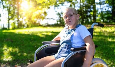 Parkta yürürken tekerlekli sandalyede oturan genç, sakat bir genç, sakat bir çocuk, sakat bir çocuk.