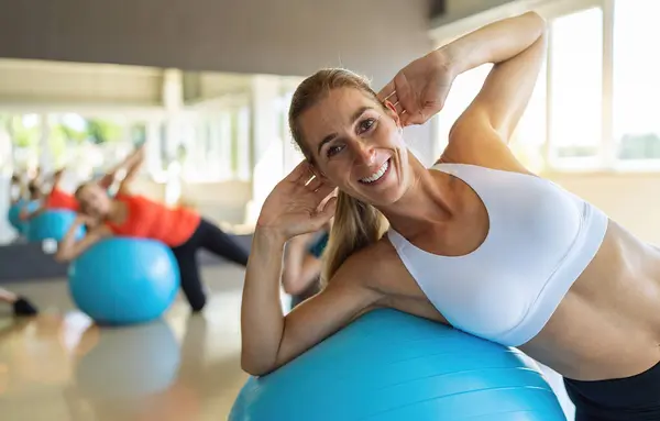 smiling woman flexing abdominal muscles with exercise ball in gym. Healthy sports lifestyle, Fitness, Healthy concept.