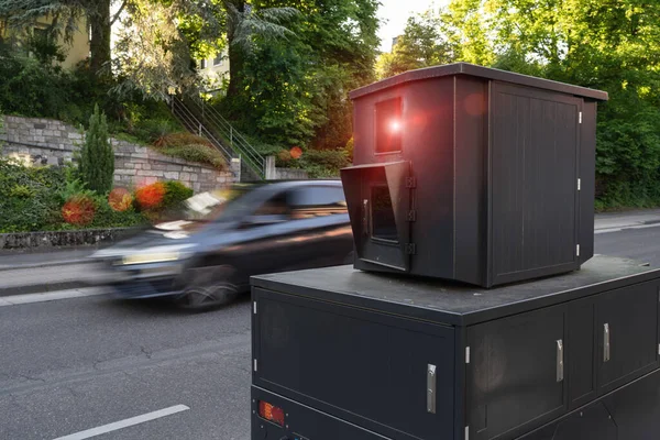 Portable speed camera on side of road capturing a speeding car in motion, residential area
