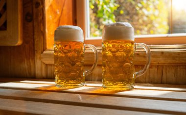 İki bira bardağı köpüklü bira bir çıkıntıda dinleniyor, güneş ışığını yakalıyor. spa ve sağlık konsepti görüntüsü