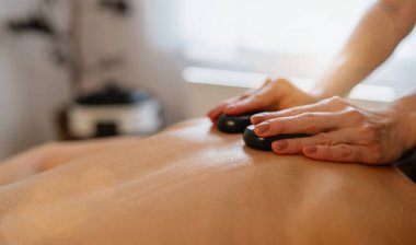 Terapistin elleriyle sıcak taş masajı yapan birine yakın çekim. Güzellik Salonu Wellness Otel Görüntü