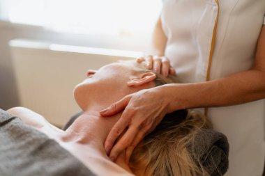 Uzanmış bir kadına boyun ve omuz masajı yapan bir terapistin yakın çekimi. Güzellik Salonu Wellness Otel Görüntü