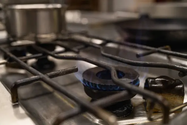 blue fire flames from a professional kitchen stove top. Gas cooker with burning flames of propane gas. Industrial Luxury hotel cooking resources and economy concept image.