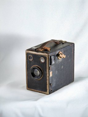 Deri kayışı olan klasik bir siyah kutu kamerası beyaz arka planda izole edilmiştir. Bu antika nesne eski teknolojiyi, nostaljiyi ve fotoğraf tarihini temsil ediyor..