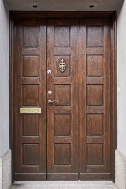 Kapı tokmağı ve sapı olan ahşap bir giriş kapısı.