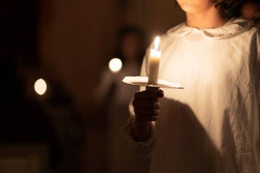 Ellerinde mum tutan insanların resmi. Noel ve Lucia tatilleri