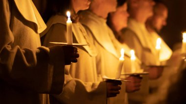 Ellerinde mum tutan insanların resmi. Noel ve Lucia tatilleri