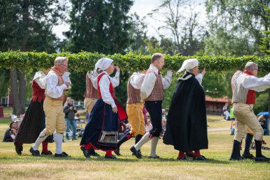 Vaxjo, İsveç, Haziran 2023: İnsanlar İsveç Midsommar Festivali sırasında geleneksel sargılarla Maypole etrafında toplandı