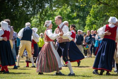 Vaxjo, İsveç, Haziran 2023: İnsanlar İsveç Midsommar Festivali sırasında geleneksel sargılarla Maypole etrafında toplandı