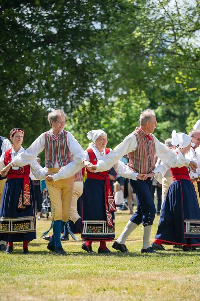 Vaxjo, İsveç, Haziran 2023: İnsanlar İsveç Midsommar Festivali sırasında geleneksel sargılarla Maypole etrafında toplandı
