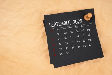 Kahverengi kağıt üzerinde raptiye ile Eylül 2025 siyah takvim sayfası.
