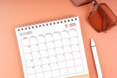 Kahverengi güneş gözlüklü 2025 Aralık masa takvimi. Tam üstte. Takvim ve anımsatma kavramı.