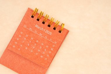 Mart 2025 için Mini kırmızı masa takvimi Eski kahverengi kağıt arkaplan, düz yatıyordu.
