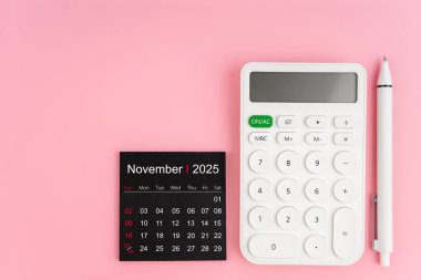 Kasım 2025 takvim ve beyaz hesap makinesinin üst görünümü pembe arkaplanda kalem, kopyalama alanı olan konum.