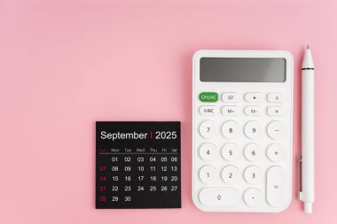 Eylül 2025 takviminin üst görünümü ve pembe arkaplanlı beyaz hesap makinesi, kopyalama alanı olan konum.