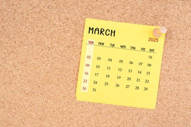 Tahta raptiyeli Mart 2025 için sarı takvim kağıdı.