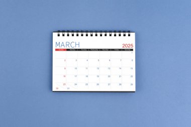 2025 Mart ayının masa takvimi mavi arka planda 2025 yıl için. Düz yatıyordu.