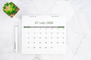 Desk calendar on month of July 2025 with pen on white marble color background. clipart