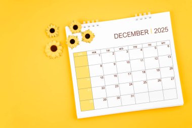 2025 Aralık masa takvimi ve sarı zemin üzerindeki ayçiçekleri, kopya alanı olan konum.