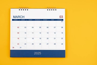 Mart 2025 iş toplantısı ya da planlama konsepti için sarı masadaki masa takvimi.