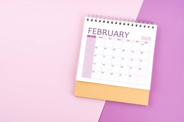 Pembe ve mor arkaplan üzerine Şubat 2025 masa takvimi.