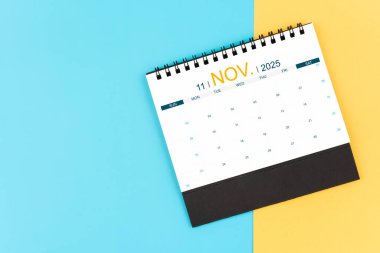 Kasım 2025 mavi ve sarı masa takvimi, iş toplantısı veya planlama konsepti.