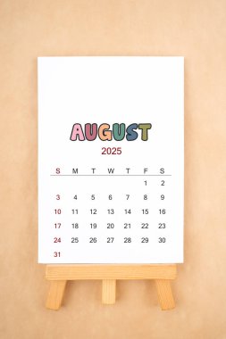 Ağustos 2025 takvim sayfası eski kahverengi arka planda ahşap sehpa ile.