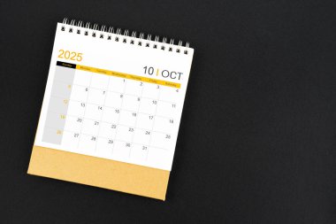 Siyah deri arka planda Ekim 2025 masa takviminin üst görünümü.