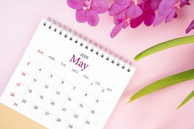 Mayıs 2026 'da çiçek açan pembe orkideli masa takvimi. Derisi yüzülmüş.