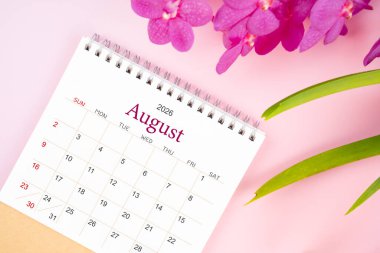 Ağustos 2026 'da çiçek açan pembe orkideli masa takvimi. Derisi yüzülmüş.