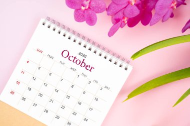 Ekim 2026 'da çiçek açan pembe orkideli masa takvimi. Derisi yüzülmüş.