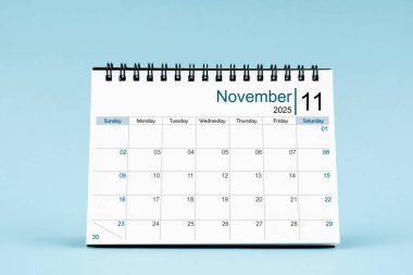 2025 Kasım ayının masa takvimi yumuşak mavi arkaplan üzerine.