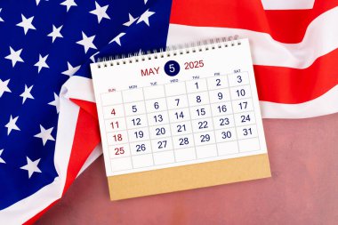 Bir Mayıs 2025 Aylık masa takvimi ve Amerika Birleşik Devletleri bayrağı.