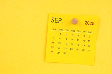 Eylül 2025 takvim sayfası sarı arkaplanda raptiye ile.