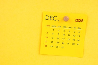 Sarı arkaplan üzerinde raptiye bulunan Aralık 2025 takvim sayfası.