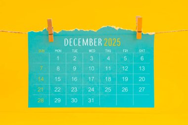 Aralık 2025 takvim yırtılması sarı arka planda kahverengi iple asıldı.