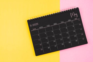 Mayıs 2025 Sarı ve pembe arkaplan üzerinde siyah takvim spirali.