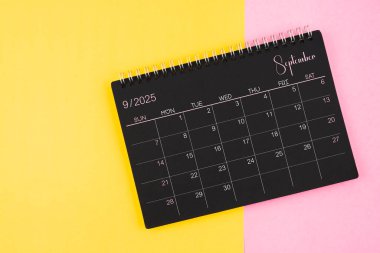 Eylül 2025 Sarı ve pembe arkaplan üzerinde siyah takvim spirali.