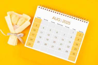 2025 Ağustos 'unda sarı arka planda buket çiçekli masa takvimi.