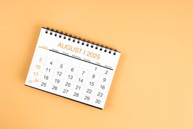 Sarı pastel arka planda Ağustos 2025 masa takviminin üst görünümü.