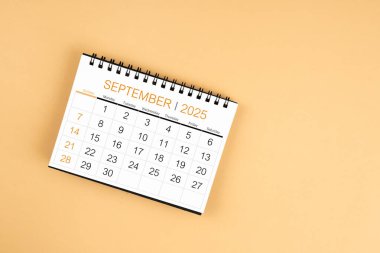 Sarı pastel arkaplan üzerine Eylül 2025 masa takvimi üst görünümü.