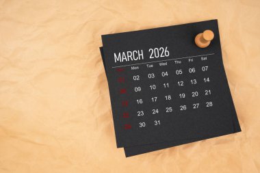 Kahverengi kağıda raptiye yapıştırılmış Mart 2026 için siyah takvim.