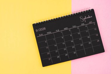 Eylül 2026 Sarı ve pembe arkaplan üzerine siyah takvim spirali.