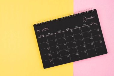 Aralık 2026 Sarı ve pembe arkaplan üzerine siyah takvim spirali.